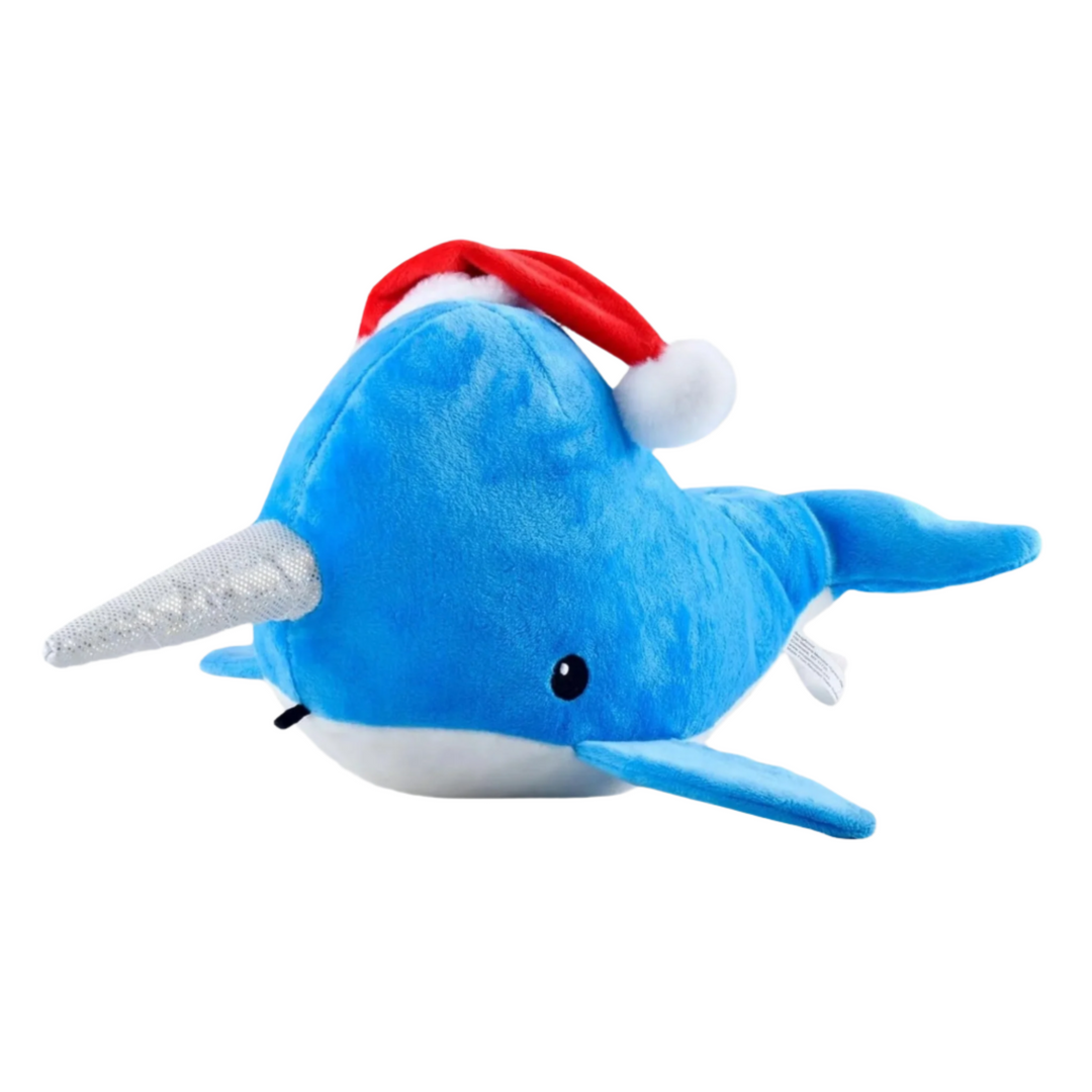 Holiday-themed blue narwhal plush toy with a red Santa hat, resting on a white background.